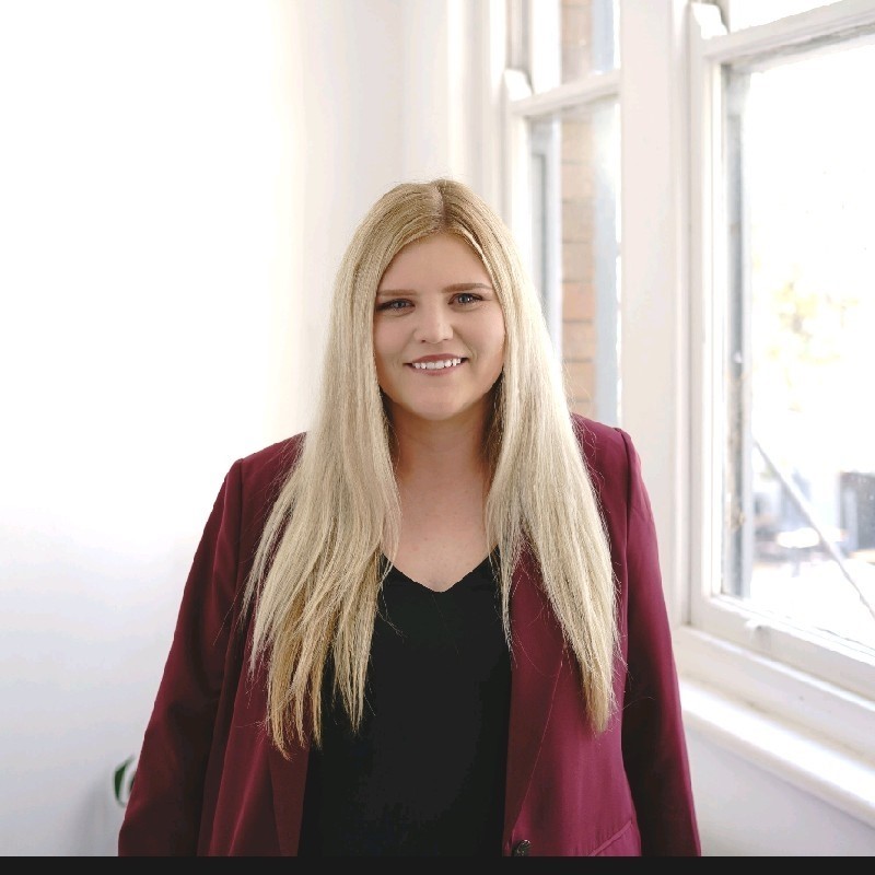 Image description: Jamie Sonneveld standing neaby window and smiling