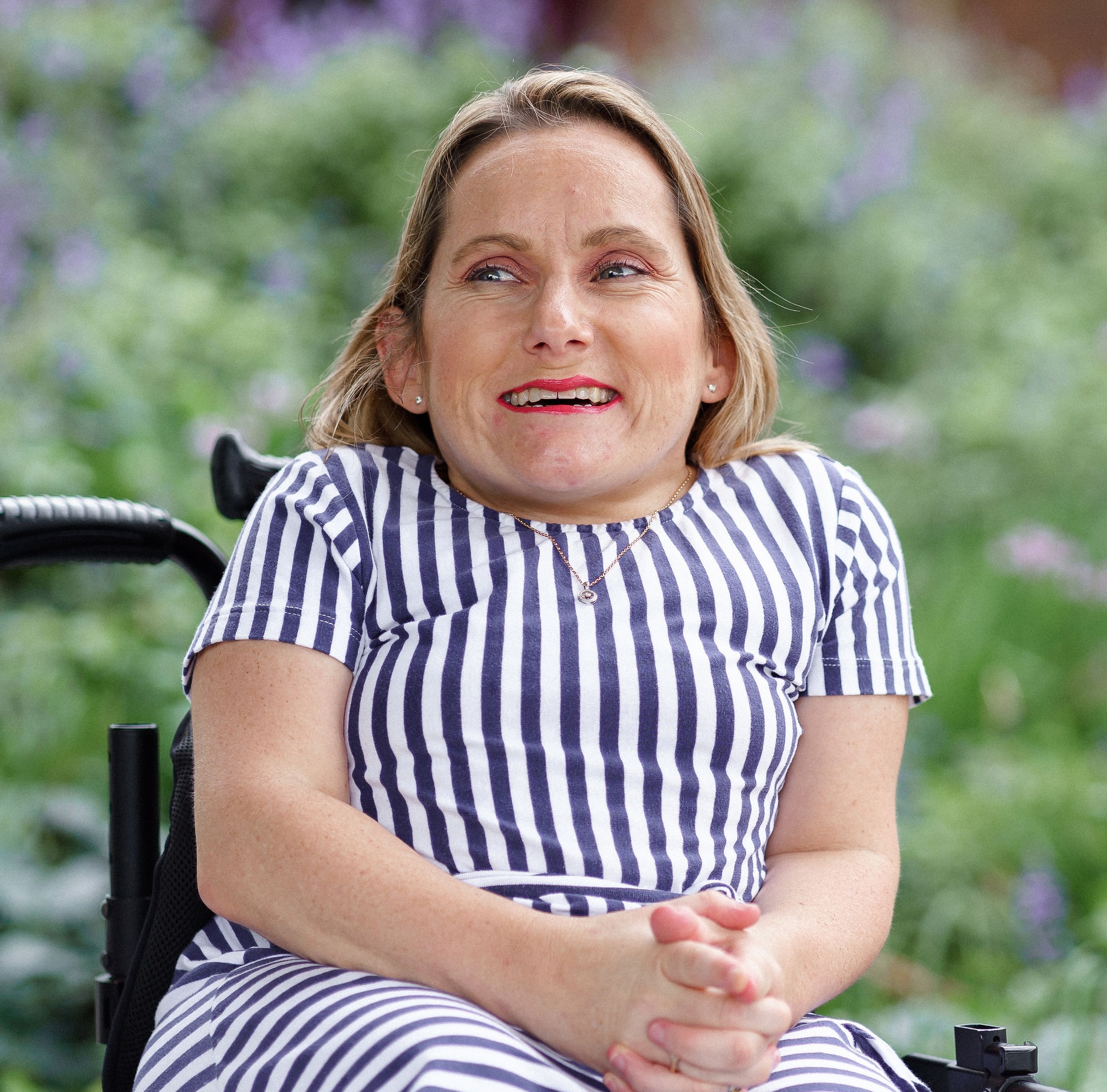Image description: Naomi Curry smiling in front of lavendar bushes