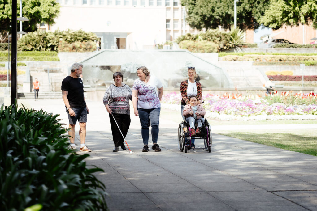 Image description: Four women and a man walking on a path through civic park